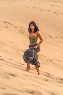 Young woman walking barefoot on the maspalomas dunes in gran canaria, enjoying the desert landscape