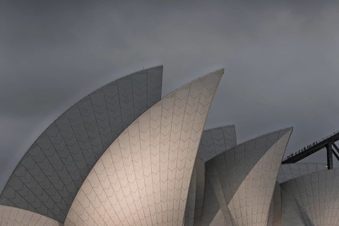 Iconic Sidney Opera House prominently against a dramatic overcast sky, showcasing modern