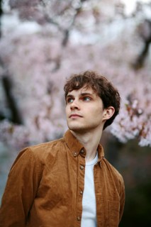 A thoughtful individual gazes into the distance, surrounded by the delicate beauty of blooming