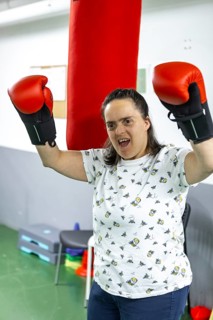 A woman with red boxing gloves enthusiastically practices boxing in a mental health residence,