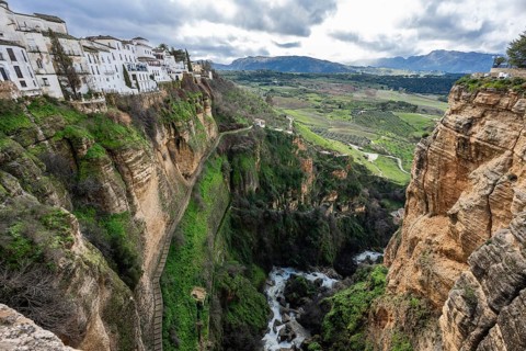 Scenic view looking down into the lush green El Tajo gorge in Ronda, showing the river and the