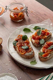 Rustic bruschetta topped with creamy cheese, marinated cherry tomatoes, and fresh spinach. Served