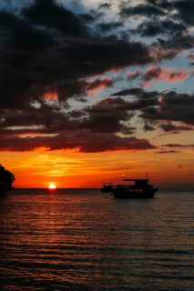 Traditional wooden boats float on the shimmering waters of Koh Rong Island, Cambodia, silhouetted