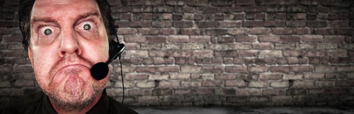 Grumpy Businessman with Frowning Face Wearing Phone Headset In Office with Brick Background Banner