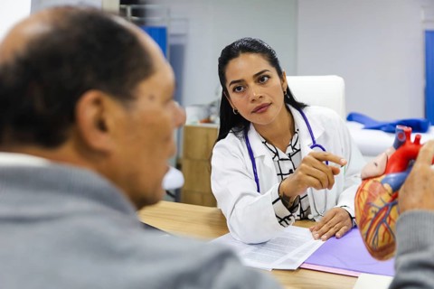 A young female doctor provides professional care to an elderly male patient in a Latin American