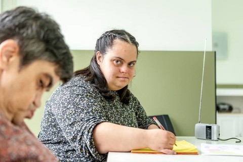 Two women participate in a creative activity at a mental health residence, fostering inclusion,