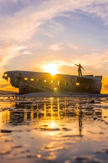 Woman on top of the Solheimasandur plane at a sunrise in Iceland
