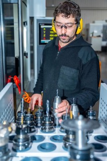 Vertical photo of a worker choosing the size of a lathe to work in a cnc factory