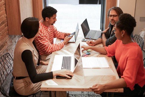A group of diverse professionals collaborate in a modern coworking space, sharing ideas and working