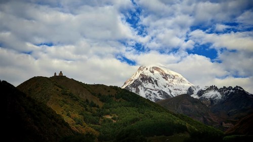 Snowy mountain peak, Kazbek, at sunset, Gergeti church on hill in the foreground, Stepantsminda,