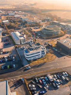View from above of an industrial area with several buildings and cars, surrounded by streets and