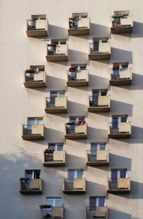 Facade of a residential building with balconies and long shadows on a sunny wall in a beautiful,