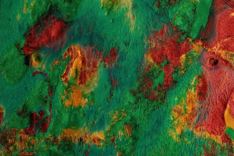 An abstract texture of metallic paints in vibrant green and red hues, ideal for artistic