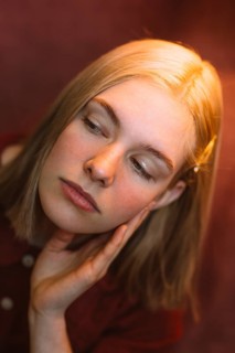 A serene portrait captures a teenager in thoughtful pose, hands gently resting on her face. Warm