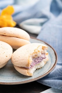 Meringues cakes with cup of coffee on a black concrete background and blue linen textile. Side