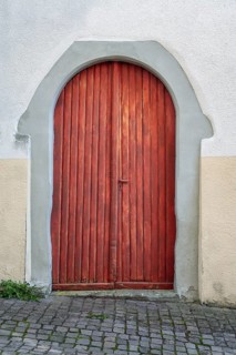 Arc-shaped wooden door surrounded by a grey stone frame in the historic old town of Überlingen am