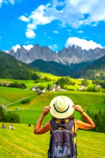 Female tourist holding her straw hat while admiring the breathtaking landscape of the dolomites