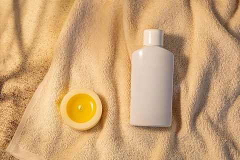 A serene spa setting featuring a bottle of lotion and a lit yellow candle, beautifully placed on a