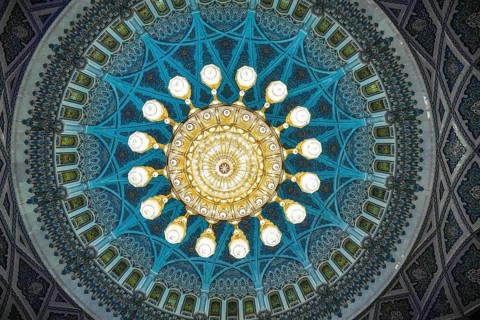From below a captivating view of the ornately decorated dome and chandelier inside Sultan Qaboos