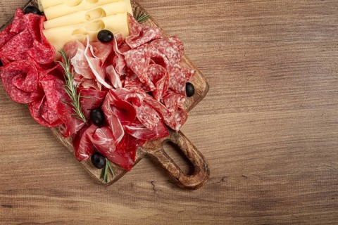 Assorted meat, appetizer, prosciutto, salami and ham, with maasdam cheese and olives, on a wooden