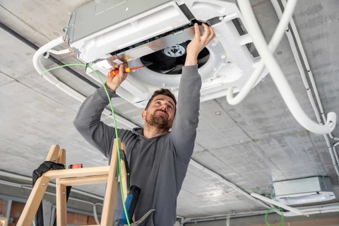 Professional technician installing a new air conditioning ventilation system on a concrete ceiling
