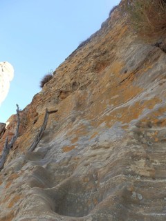 Steep climb to Abuna Yemata Guh rock church, steep rock wall with blue sky in the background,