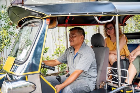 A Thai male tuk tuk driver and a female tourist exploring the city of Chiang Rai in Thailand. The