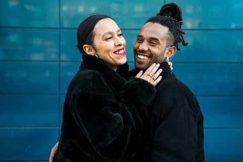 A multiethnic couple shares a joyful embrace, symbolizing unity and diversity. The modern backdrop