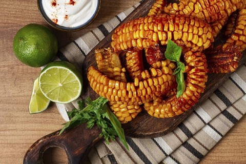 Corn ribs, with cream sauce, spices and lime, appetizer, on a wooden cutting board, homemade, no