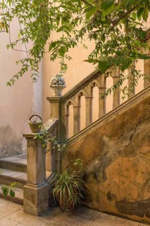 Weathered stone staircase with sturdy railings and plants, surrounded by nature and antique charm,