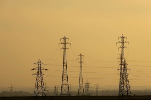 Electricity pylons and power lines silhouette at sunset, England, United Kingdom