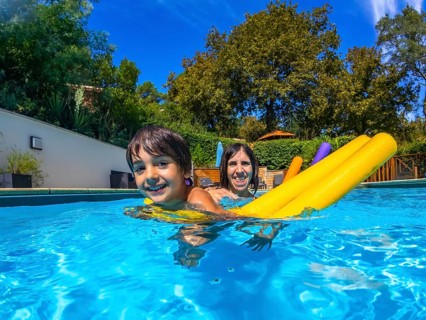 Family enjoying a sunny summer day in a blue outdoor pool, mom and child laughing while playing