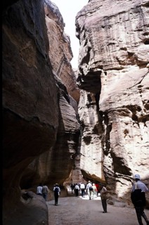 Tourists walking through a narrow passageway (siq) to the entrance of the archaeological site in