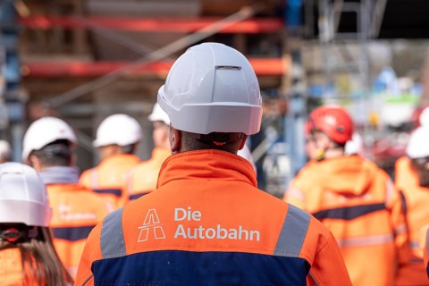 Autobahn GmbH employees wearing glowing protective clothing and safety helmet, on a construction