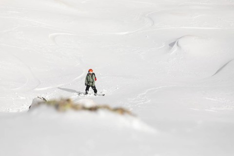 A snowboarder navigates through untouched powder in a remote mountain terrain. This exhilarating