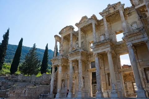 Impressive ancient façade with gigantic columns surrounded by cypresses and hills, Celsus Library,