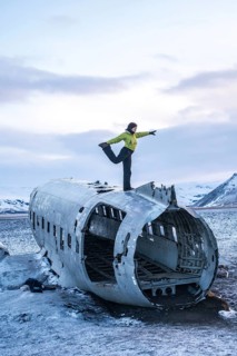 Woman on top of Solheimasandur plane doing meditation yoga in Iceland in winter