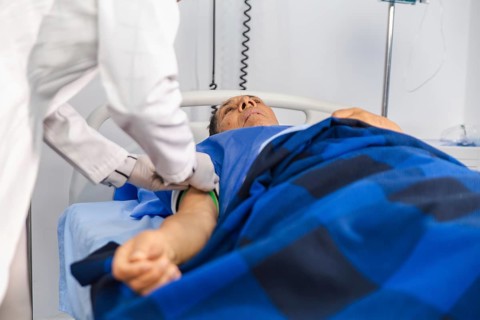 A female doctor is providing attentive care to an elderly patient lying in a hospital bed,