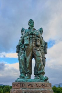Three soldiers standing in a bronze sculpture, clouds in the sky, words 'United We Conquer',