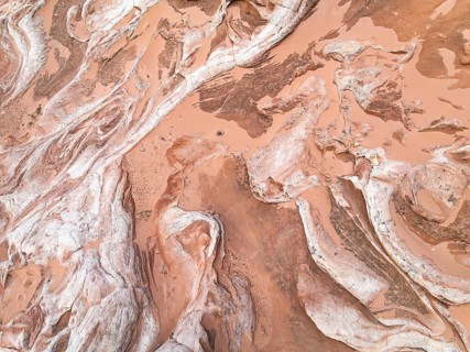 Aerial view of a red desert landscape, showcasing intricate textures and patterns formed by natural