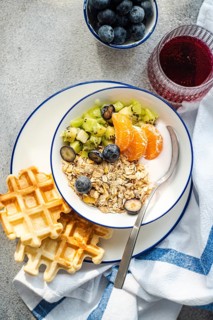 A delightful breakfast spread featuring a bowl of granola with fresh kiwi, tangerine, blueberries,
