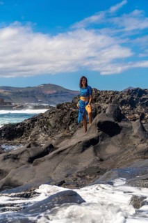 Tourist posing on volcanic rocks at the beach in arucas, gran canaria, canary islands, spain,