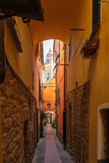 View through a picturesque narrow alley of the medieval old town to the tower of the baroque church