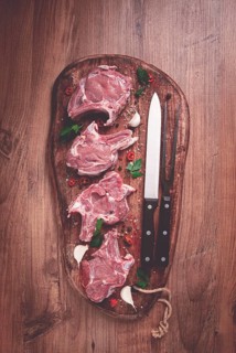 Raw calf meat, meat on the bone, meat for barbecue, cutting board, with spices and herbs, top view