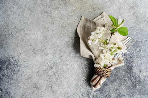 An elegant table setting with a folded linen napkin, delicate white flowers, and silver fork and