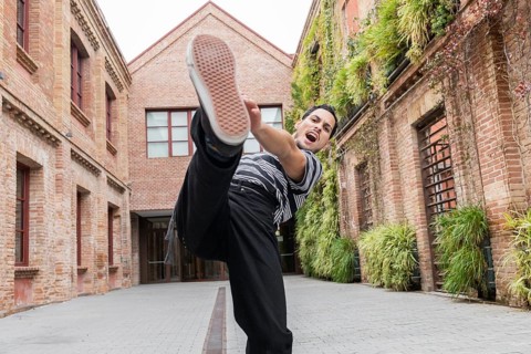 A dynamic Cuban dancer in mid-kick, radiates energy in a vibrant urban courtyard. Surrounded by