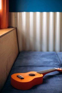 A cozy Mexican interior features an acoustic ukulele resting on a plush blue sofa. The vibrant
