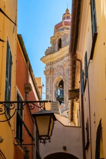 View through a picturesque narrow alley of the medieval old town to the tower of the baroque church