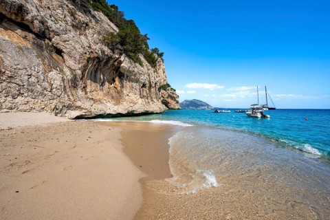 Sandy beach beach and steep cliffs at Cala Luna, Golfo di Orosei, Baunei, Sardinia, Italy