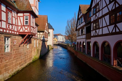 Canal between half-timbered houses, bright blue sky, historic architecture inviting and